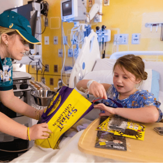 Patient receiving donation of toys and activities while in hospital bed.