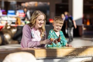 Children's Nebraska provider playing dinosaurs with young patient in hospital lobby.