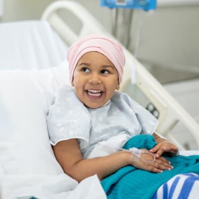 Young girl in hospital bed smiling at her provider.