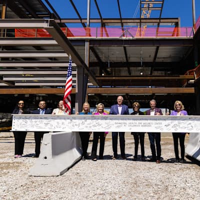 Team members standing behind final beam of the Behavioral Health and Wellness Center.
