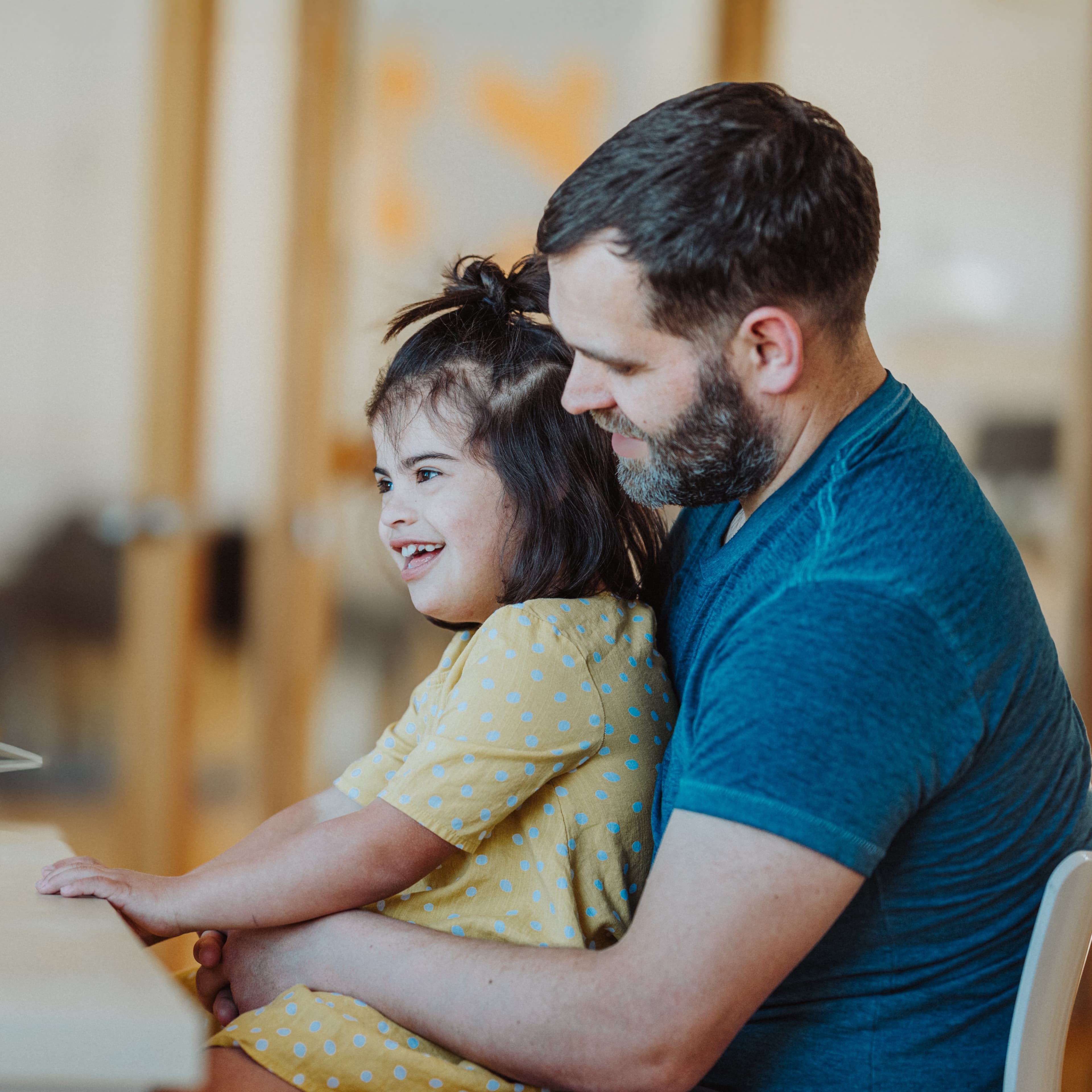 Father holding young smiling daughter on his lap