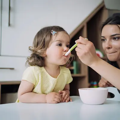 Mom spoon-feeding baby.