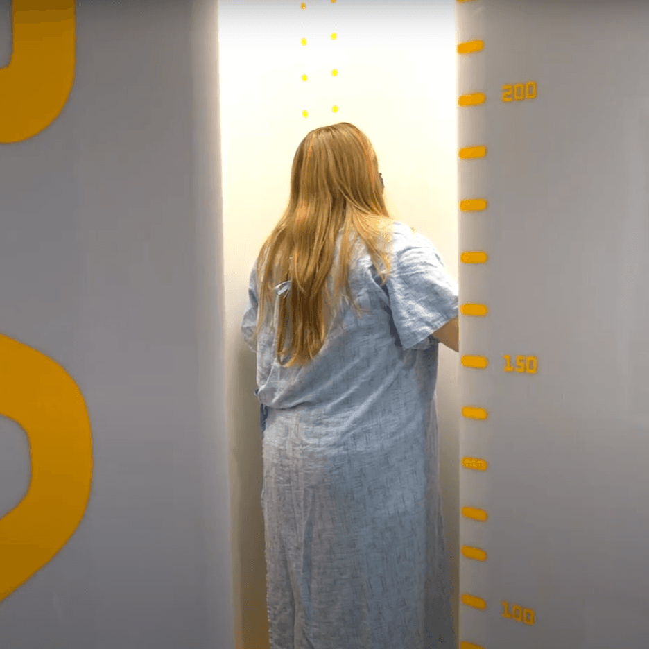 Patient standing in EOS imaging machine.